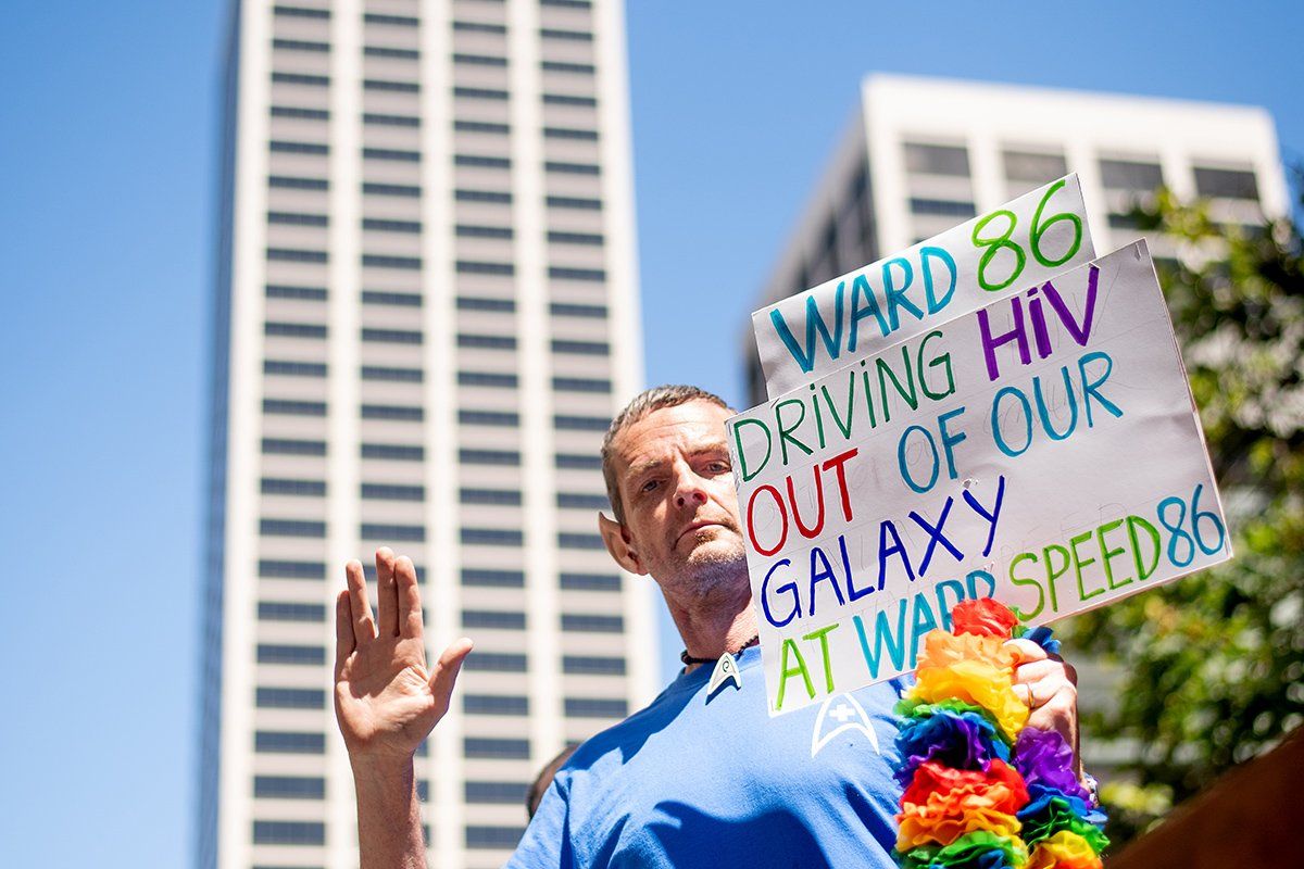Guy Vandenberg, RN, MSW, a nurse in Ward 86, gives the Vulcan salute and holds a sign that reads "Ward 86 driving HIV out of our galaxy at a warp speed 86"