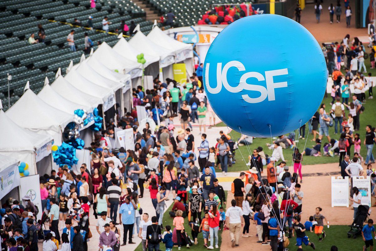 In the forground light blue baloon with letters "UCSF" in the background a big crowd of people