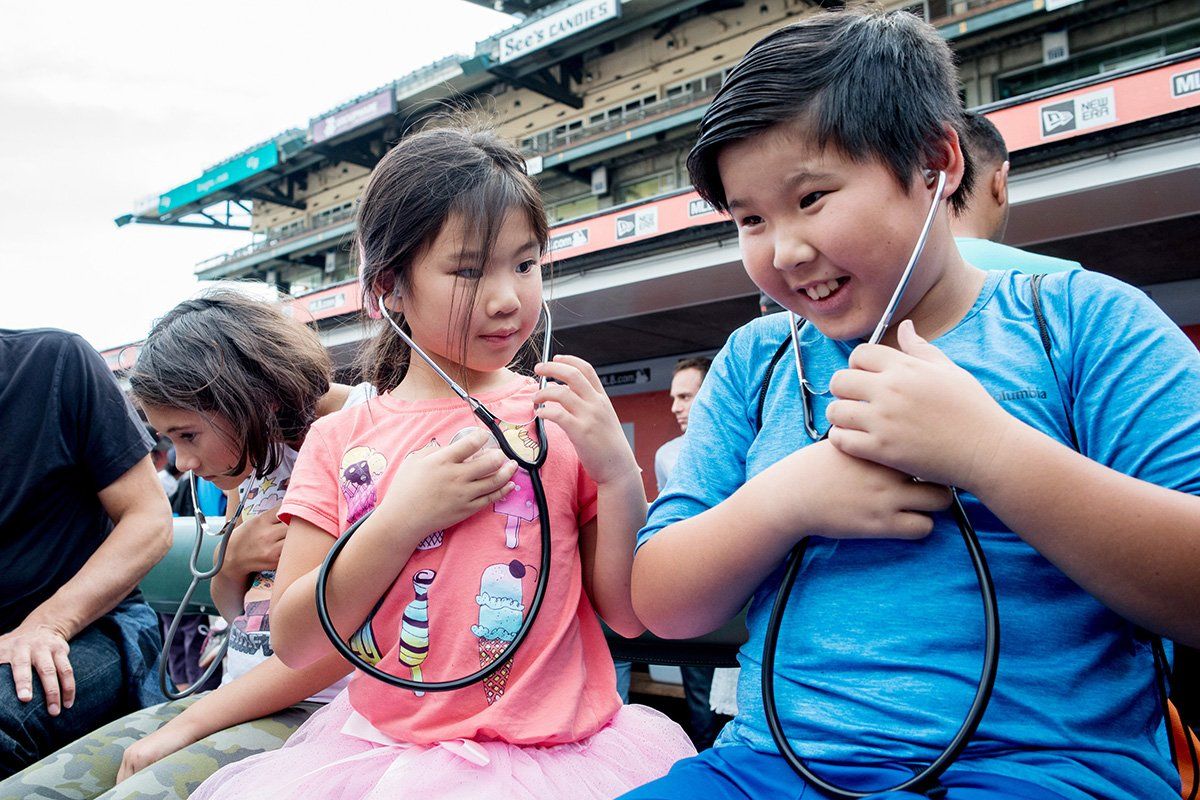 A boy and a girl listen to their heartbeats through stethoscopes