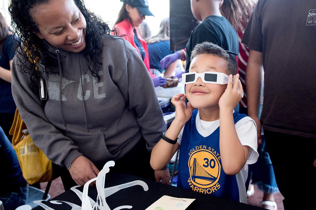 Karen Bell watches her son Isiah Hill, 6, experiment with 3D glasses at the Neurobiology booth at the Bay Area Science Festival Discovery Day