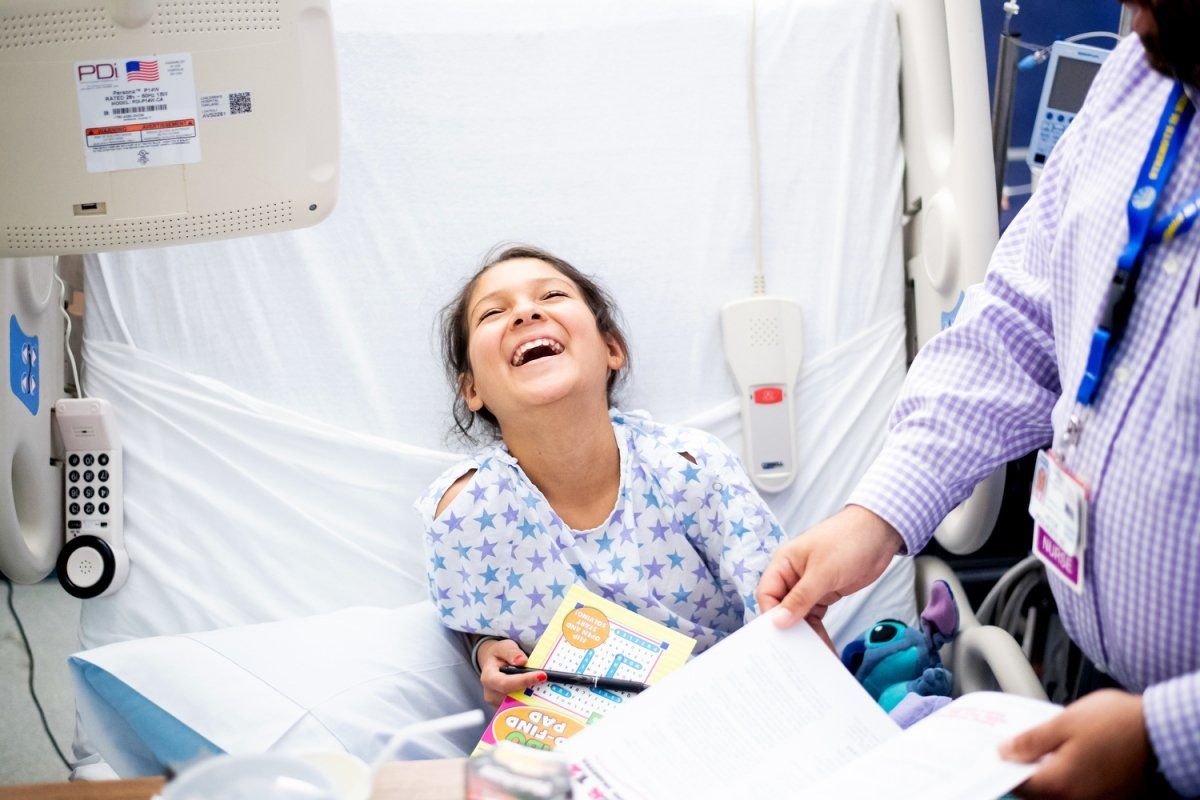 Natalia Vargas,10, laughs during a visit with nurse Victor Woolworth, RN