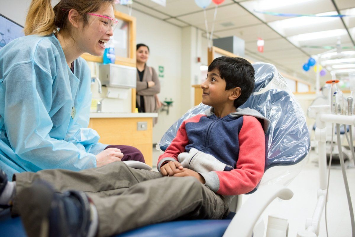 Dental student talks to a child who is sitting in the dental chair