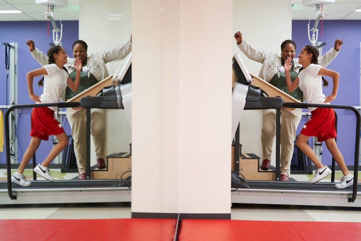 Tyrena Cockerham, PT, DPT at a gym cheers for the patient who is running on a treadmill