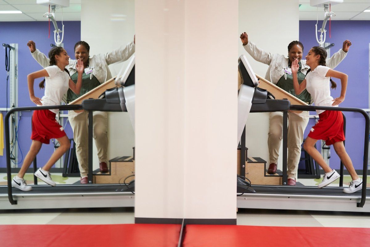 Tyrena Cockerham, PT, DPT at a gym cheers for the patient who is running on a treadmill