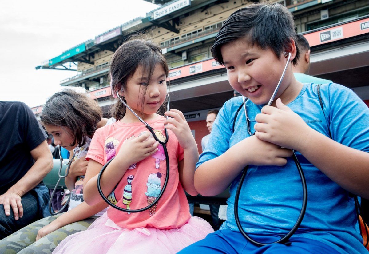 A boy and a girl listen to their heartbeats through stethoscopes