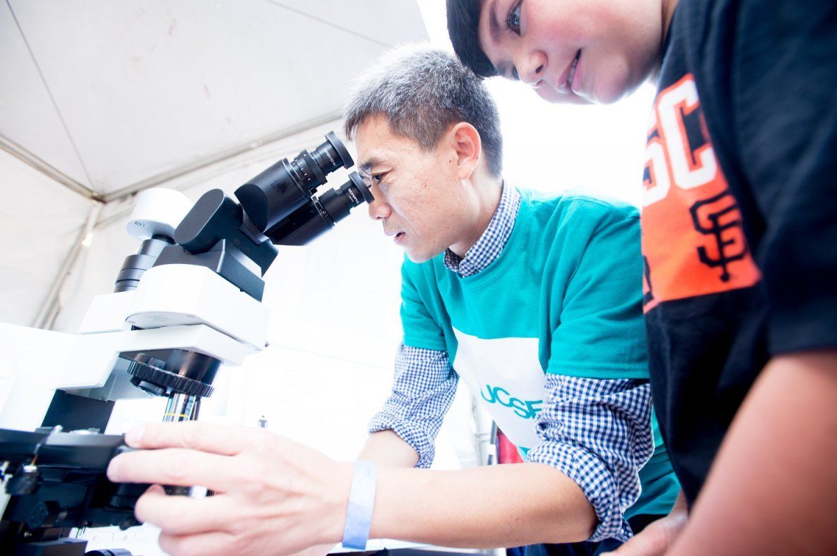 Assistant Professor Joe Qi, PhD, helps a child examine chromosomes through a microscope