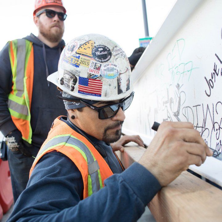 A construction worker signs the final steel beam of the Precision Cancer Medical Building before it is installed