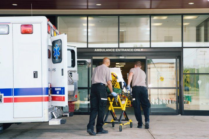 EMT taking stretchers through emergency room doors.