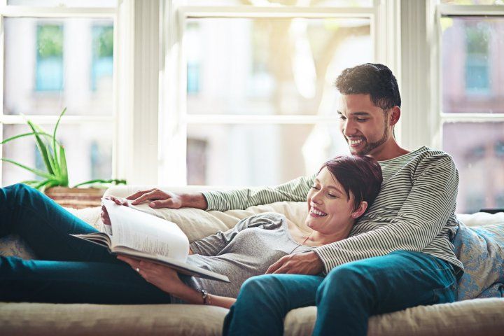 couple smiling while reading on a couch