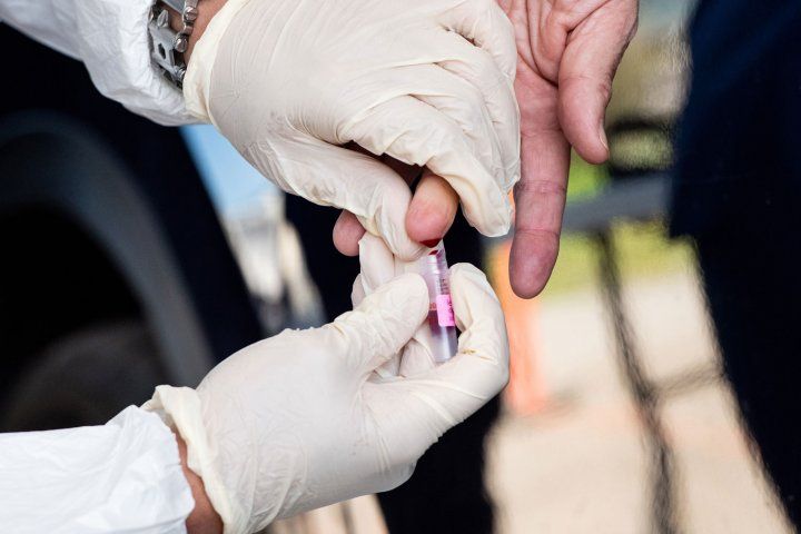 Gloved hands performing finger prick blood test