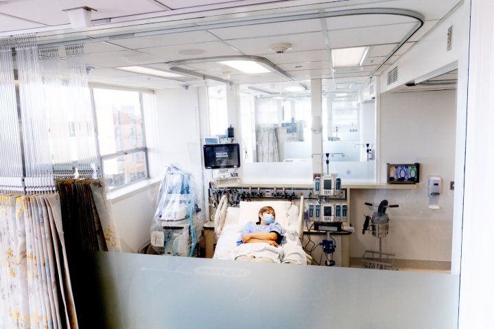 A mock patient seen through a window of an isolation room