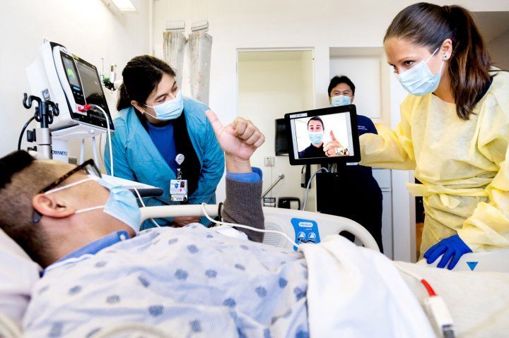 A mock patient gives a thumbs up over a video call