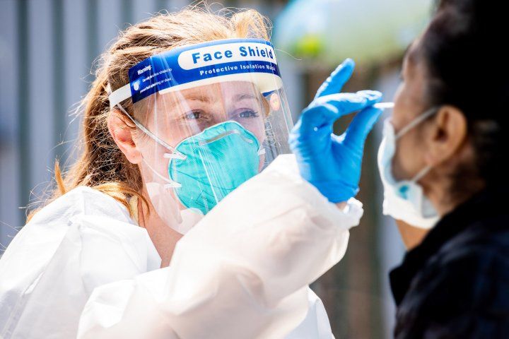 nurse administers a nasal swab for COVID-19 testing at a Mission District testing site