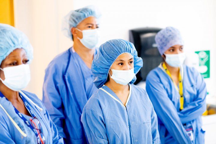 staff stand in gowns and masks