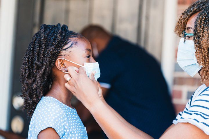 mother adjusts mask on young girl