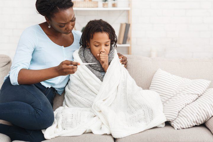 mother looks at thermometer with sick daughter