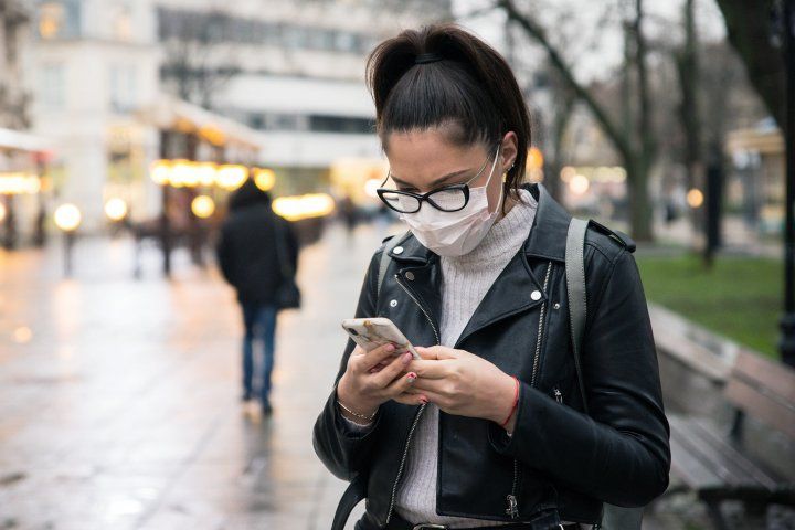 woman wearing a mask and looking at a cellphone