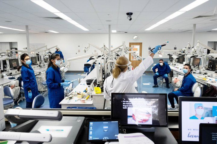 Instructor talks to a small group of students in a dental simulation lab