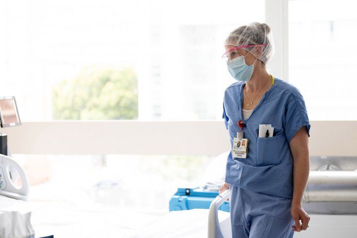 Nurse stands at end of hospital bed talking to a patient out of photo