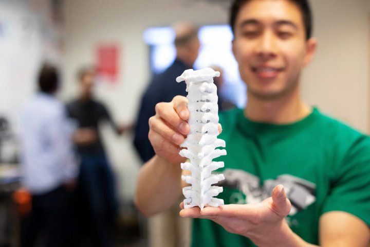 man holds a 3d-printed human spine model