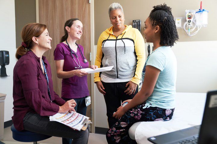 a pediatric patient and her mother talk with two doctors