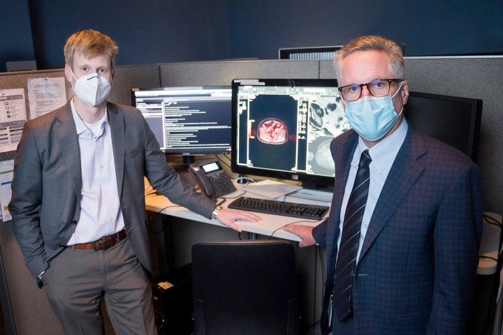 Tomas Hope and Peter Carroll stand in front of a computer with patient's scan on the screen