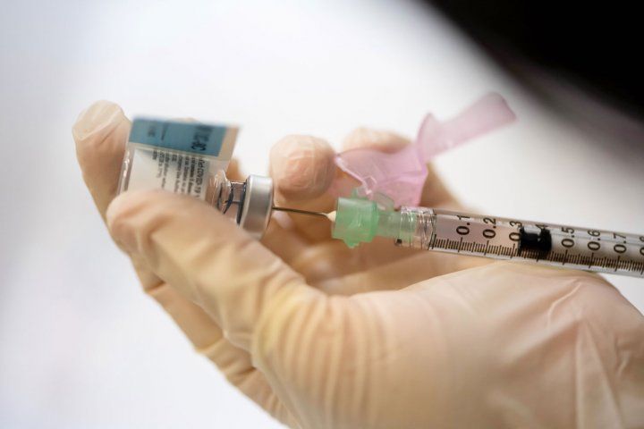 A hand holding a syringe and vial