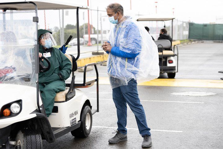 woman sits in a golf cart and talks to a man at the vaccination clinic site