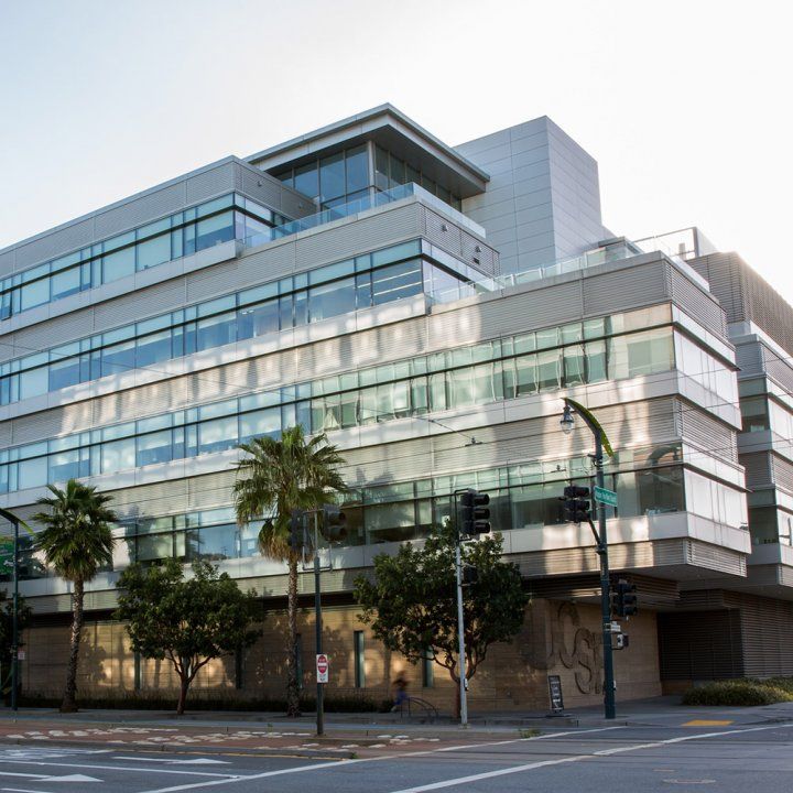 Palm trees sit in front of the mirrored angular facade of the Helen Diller Family Cancer Research Building