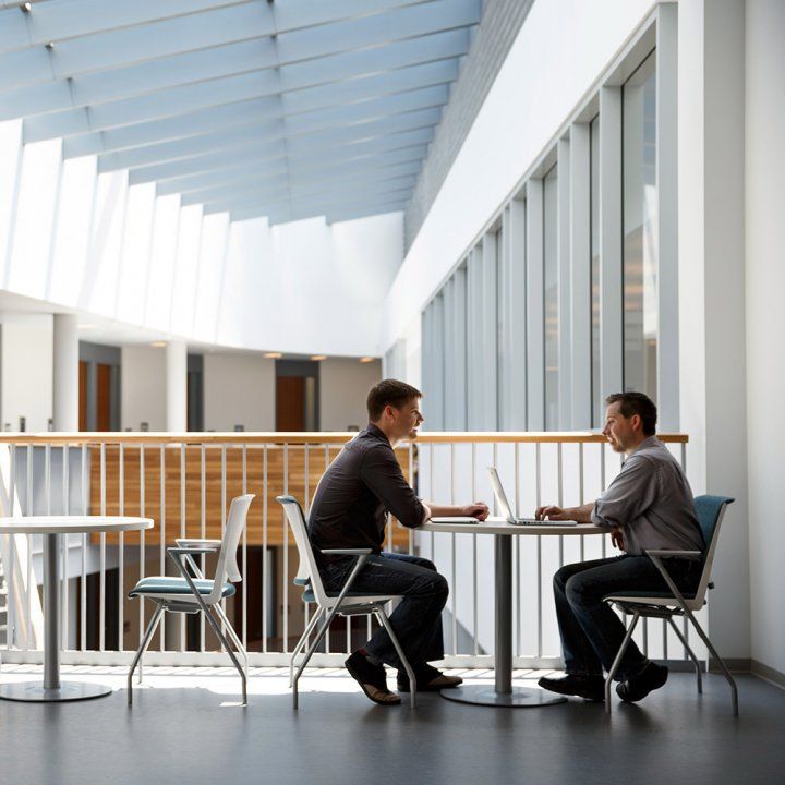 Two colleagues sit on a sunlit upper level balcony in the Sandler Neurosciences Center