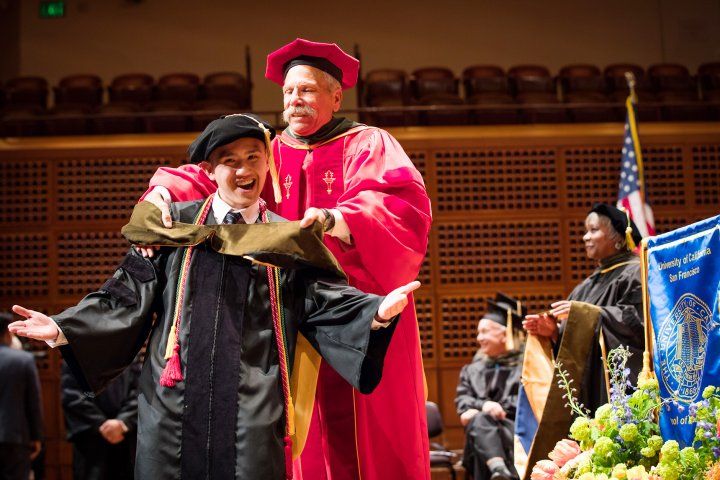 dean puts "hood" over student during commencement ceremony