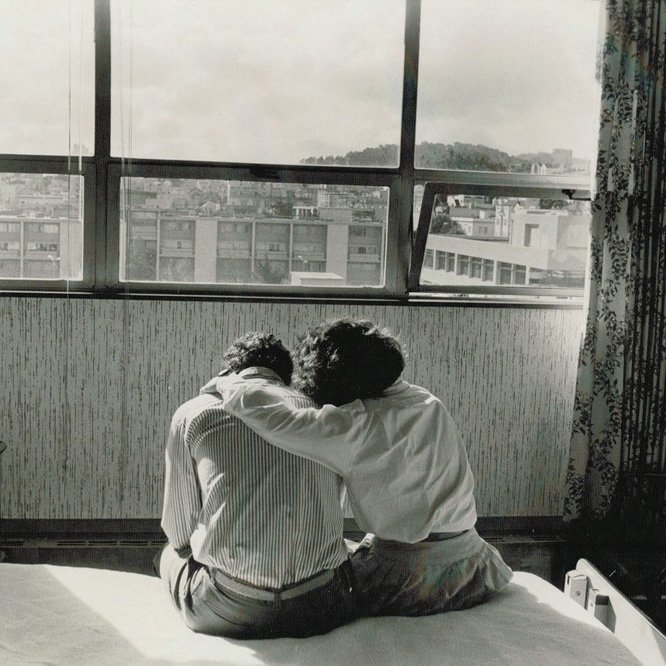 A woman puts her arm around a man while they sit on a bed in the Mount Zion hospital