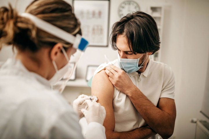 Young man wearing mask getting a shot in the arm