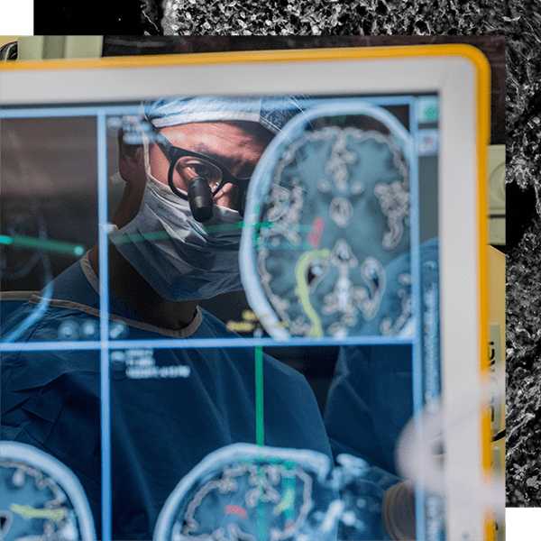 Eddie Chang reflected in a screen showing activity in the brain during surgery