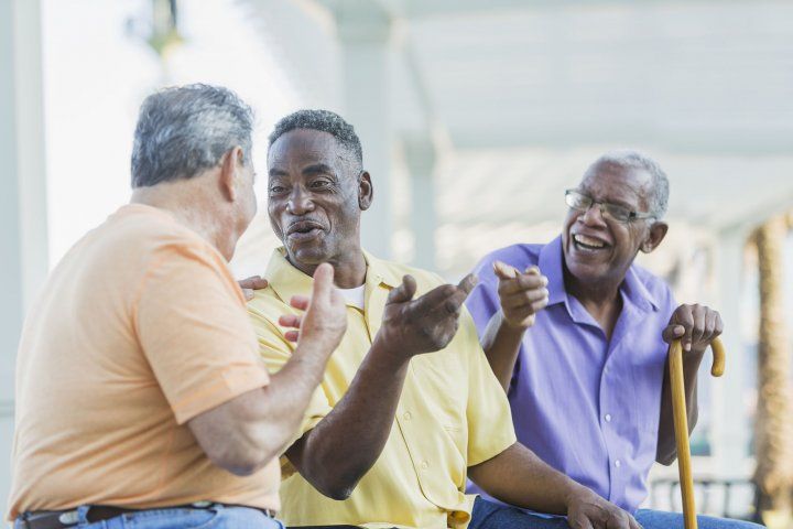 three elderly men talk while sitting