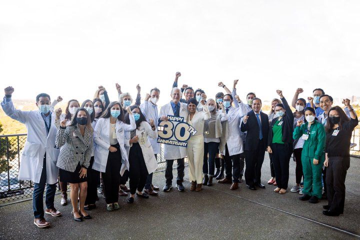 Dr. Jasleen Kukreja (center), Patrick’s surgeon, stands next to Dr. Jeff Golden of the UCSF Lung Transplant Program, who holds a sign to celebrate the program’s 30th anniversary