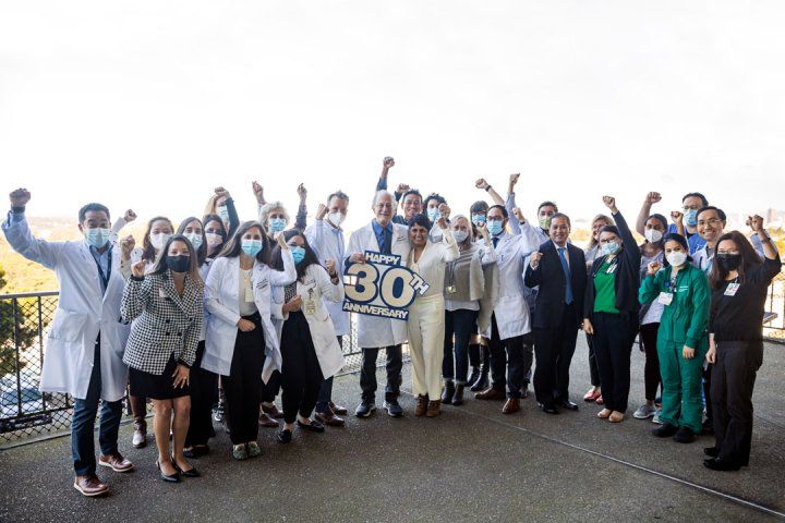 Dr. Jasleen Kukreja (center), Patrick's surgeon, stands next to Dr. Jeff Golden of the UCSF Lung Transplant Program, who holds a sign to celebrate the program's 30th anniversary