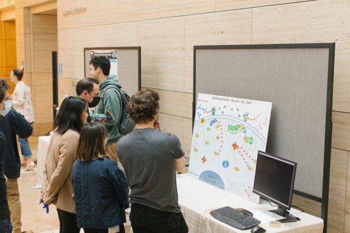 Attendees at the 2022 Byers Lecture observe a scientific poster titled "Communication Across the Cell"