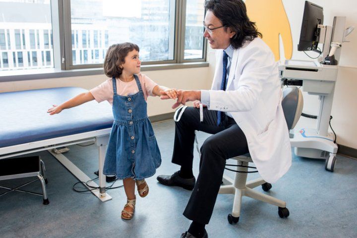 Pediatric Neurosurgeon Peter Sun examines a young girl balancing on one foot