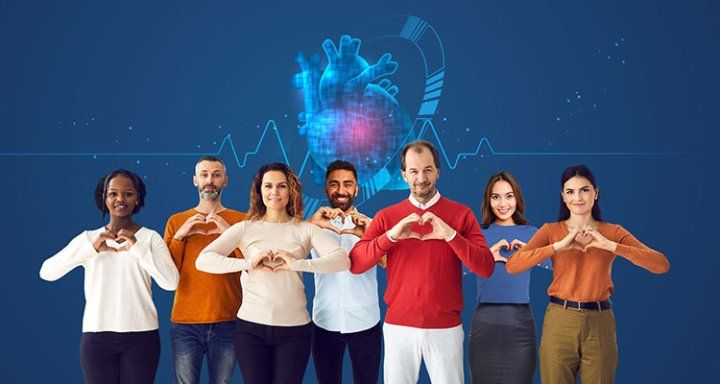 A group of people make heart signs with their hands while standing in front of a digital heart