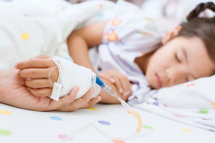 A parent holds a child's hand at a hospital