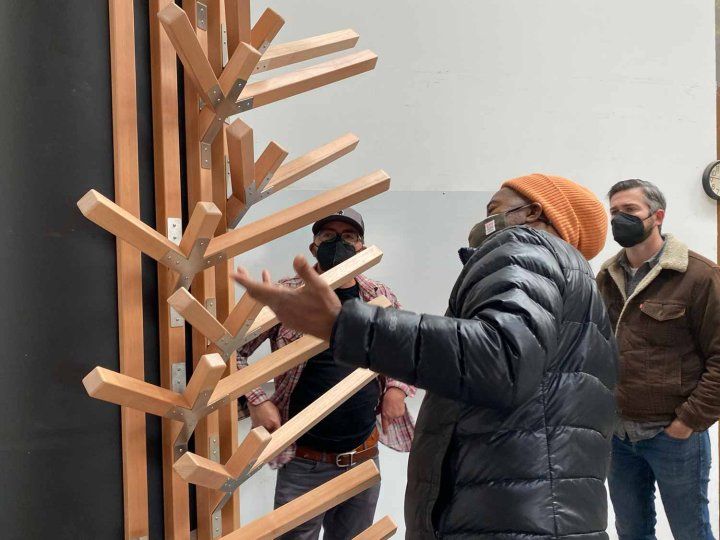 An African-American artist inspects wood planks that serve as tree branches for an art installation.