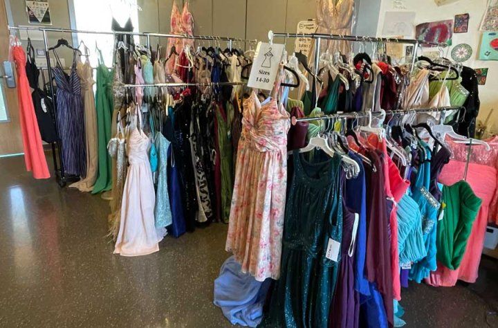 A colorful assortment of prom dresses on racks.