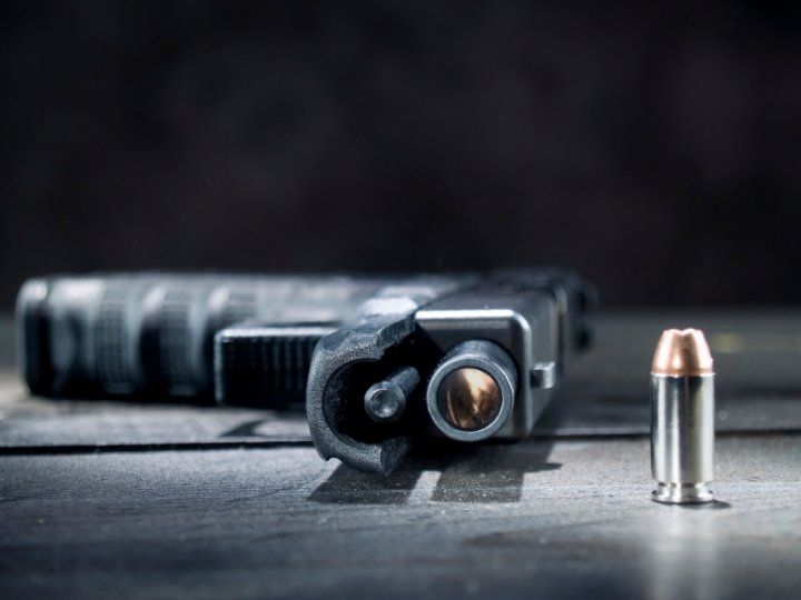 Handgun laying on its side next to a bullet.