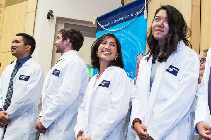 UCSF dental students line up on stage with white coats