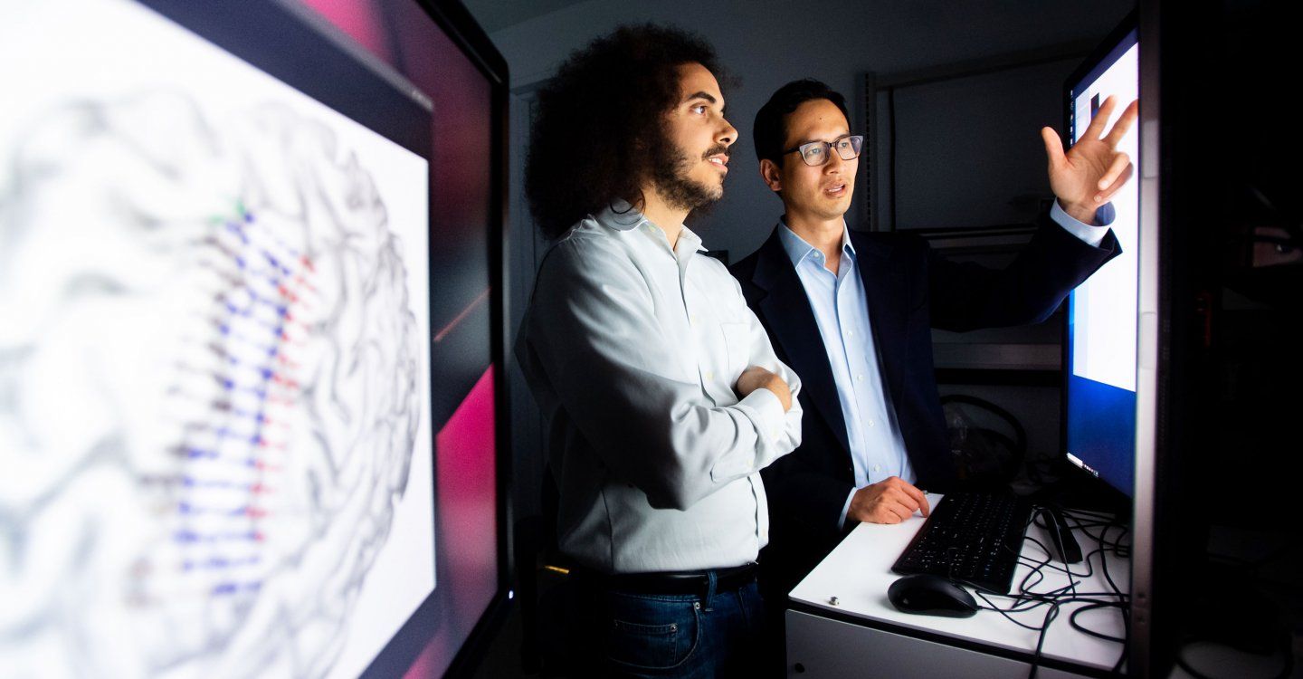 Edward Chang talking to colleague in front of computer