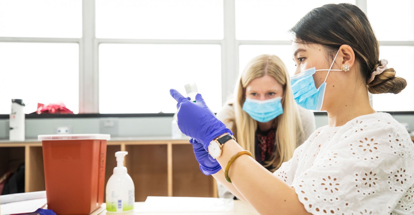 Pharmacy instructor speaks to student with masks on