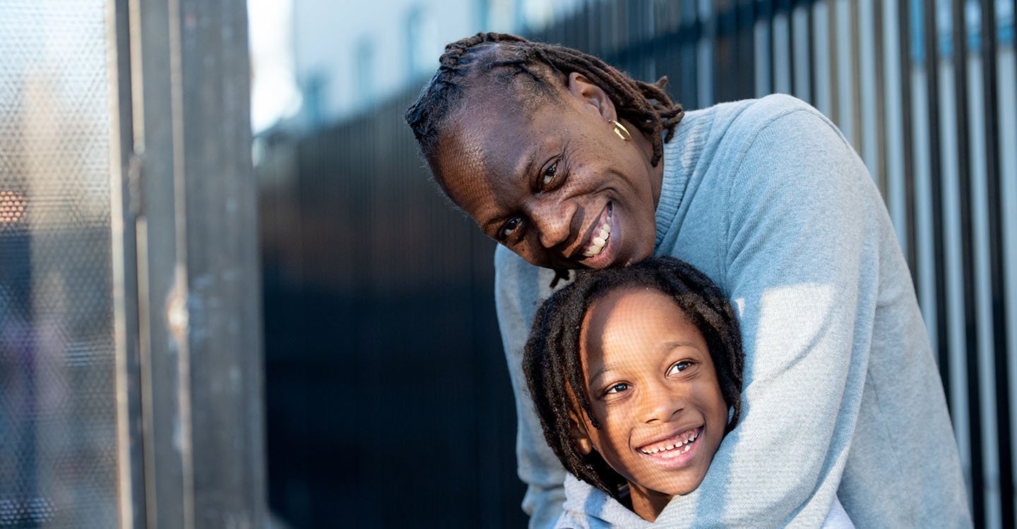 Rashetta Higgins wraps her arms around her son while both beam at the camera