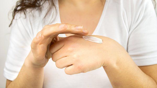 woman spreads lotion on hand