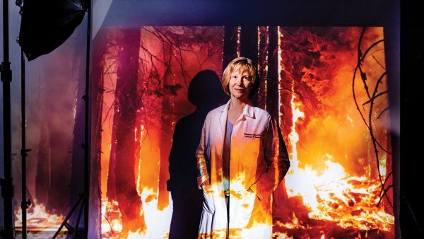 Portrait of Dr. Katherine Gundling in a photo studio setting with a projection of a forest fire.